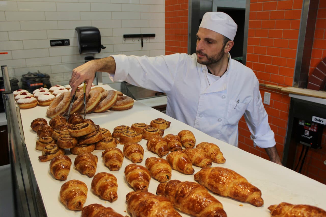 Baker arranging fresh pastries in a bakery kitchen